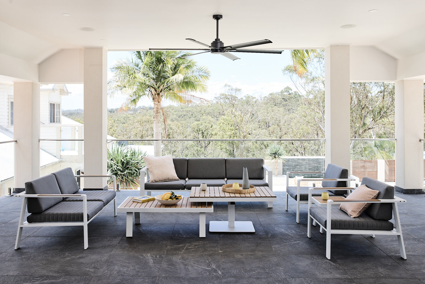 Outdoor patio furniture set with a coffee table and chairs on a concrete floor, large windows in the background.