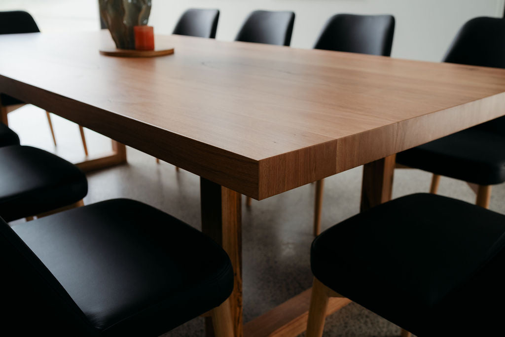 Wooden dining table with black chairs in a room setting