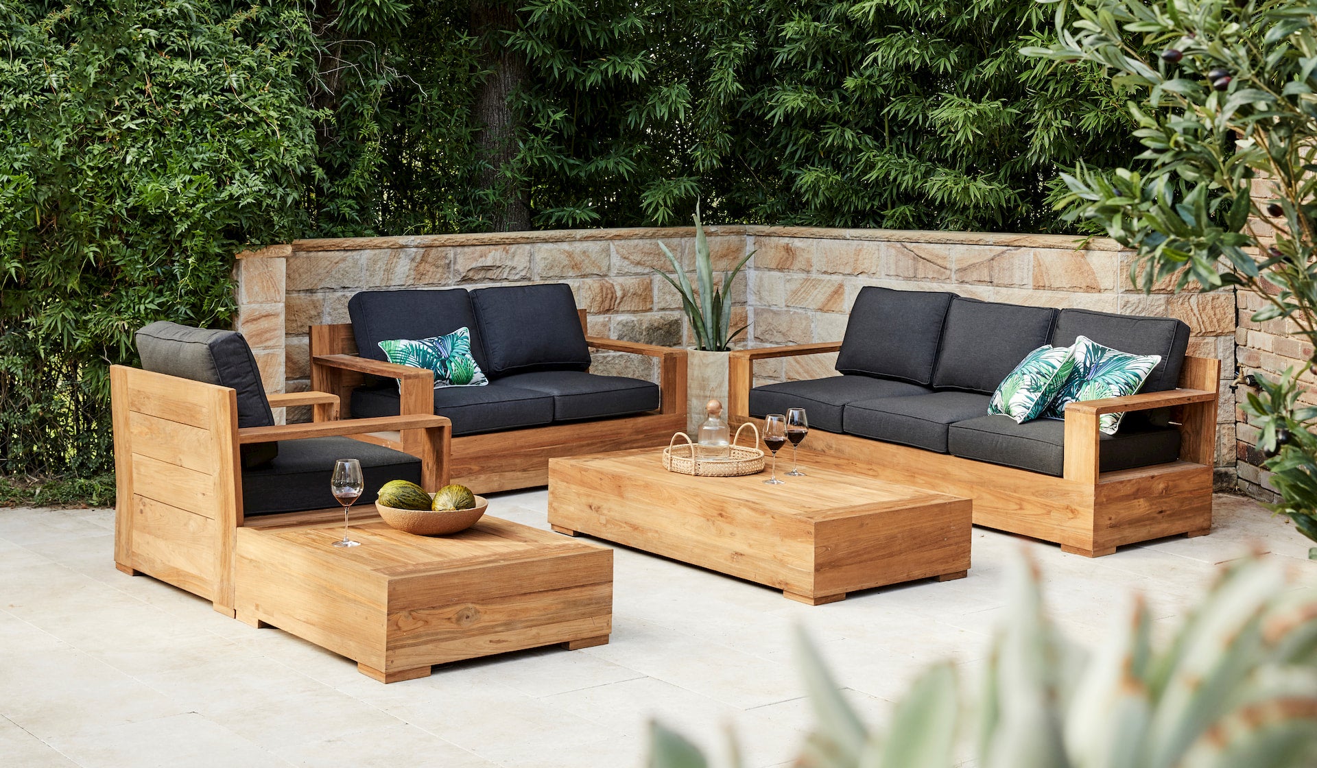 Outdoor patio furniture set with wooden chairs and table in a garden setting.